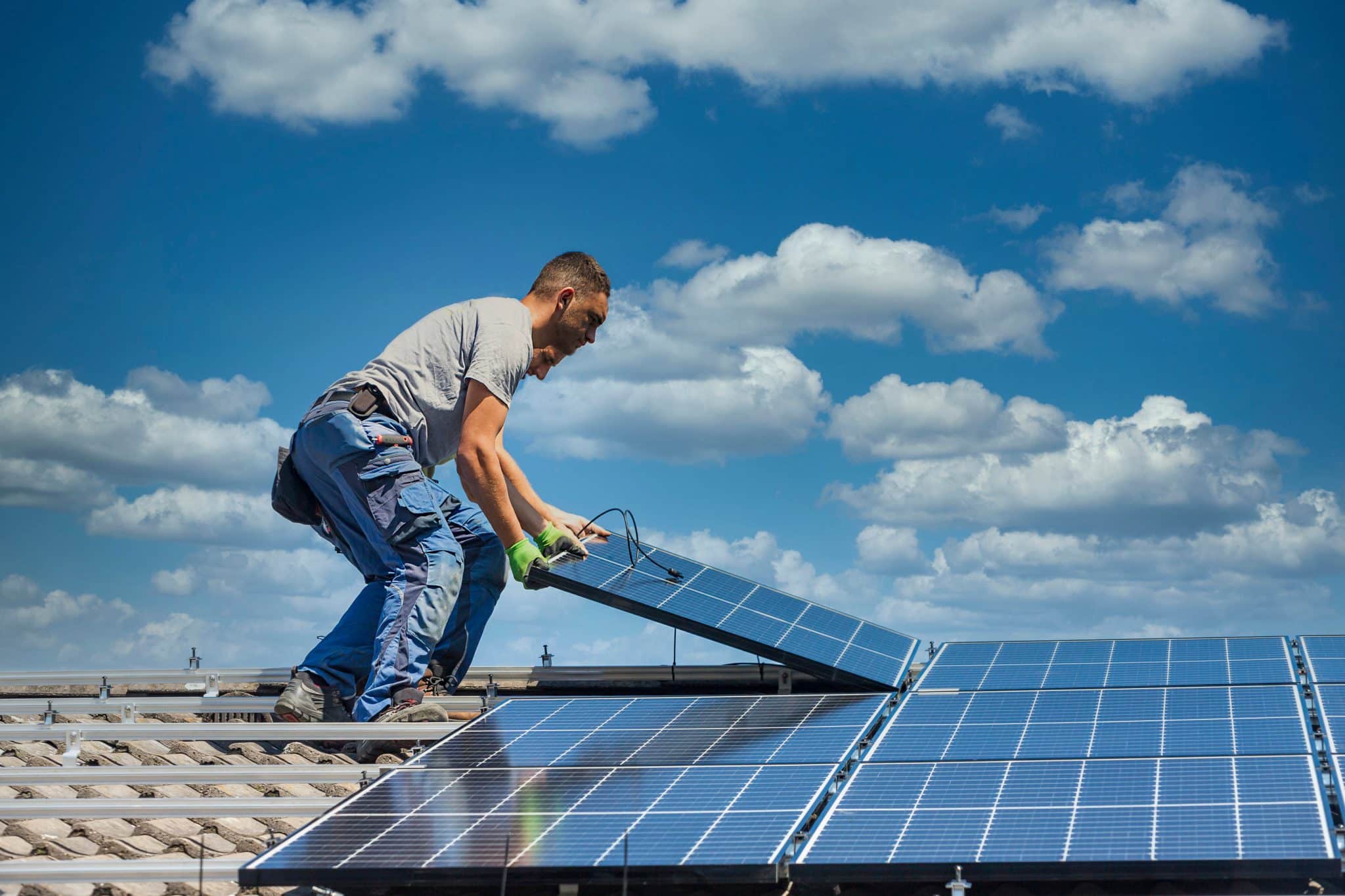 Installing solar photovoltaic panel system. Solar panel technician installing solar panels on roof. Alternative energy ecological concept.